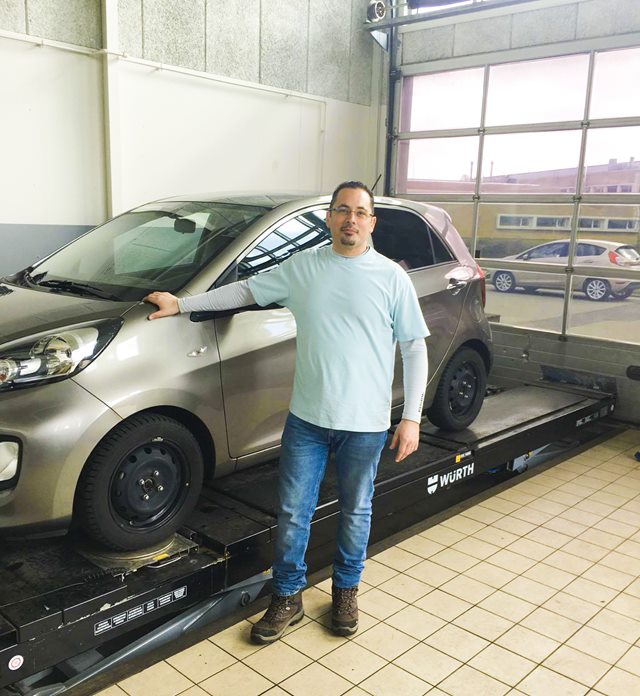 Student standing next to the car in the workshop