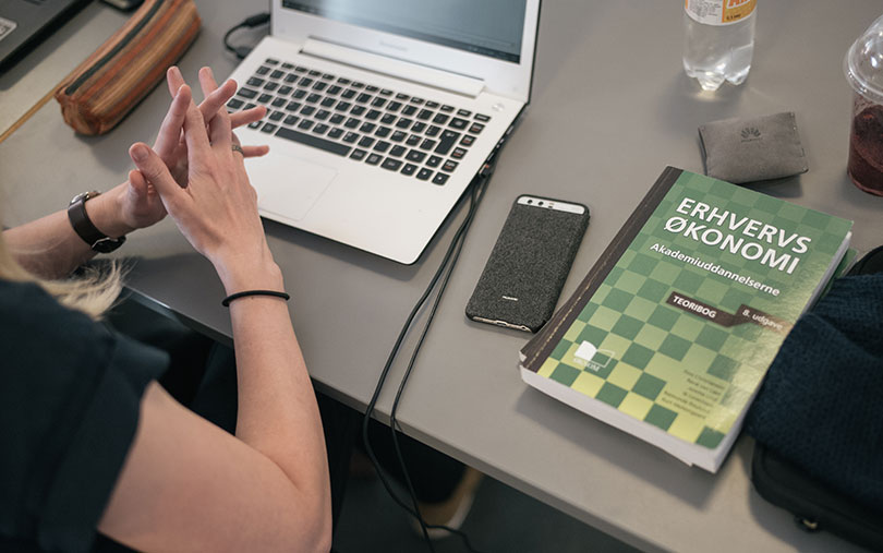 Table with laptop, phone and economic book on it