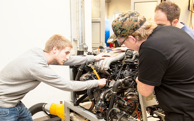 Automotive students repairing car engine 