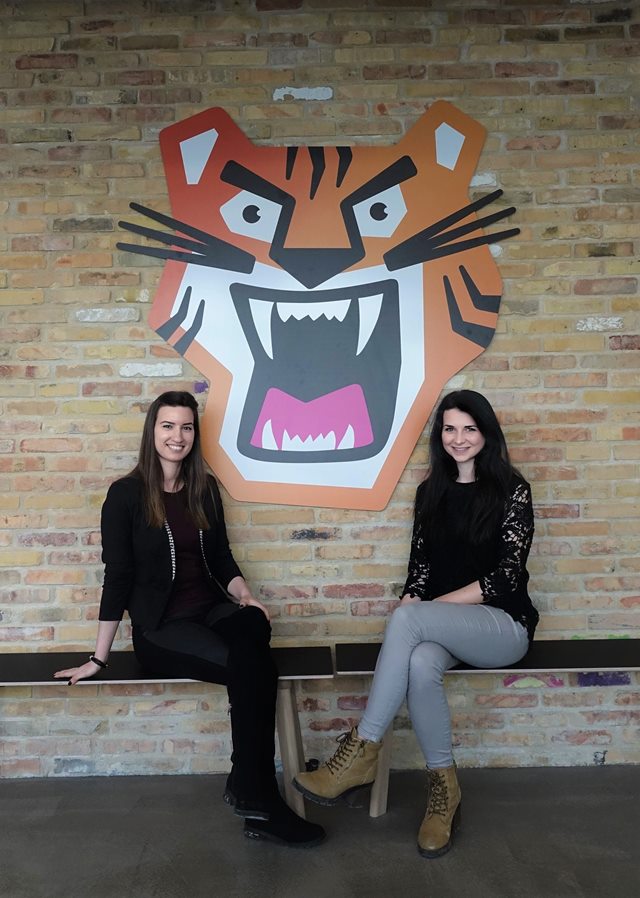 Two students sitting next to the art on the wall