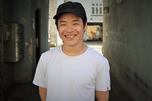 Young man in white shirt and black cap smiling